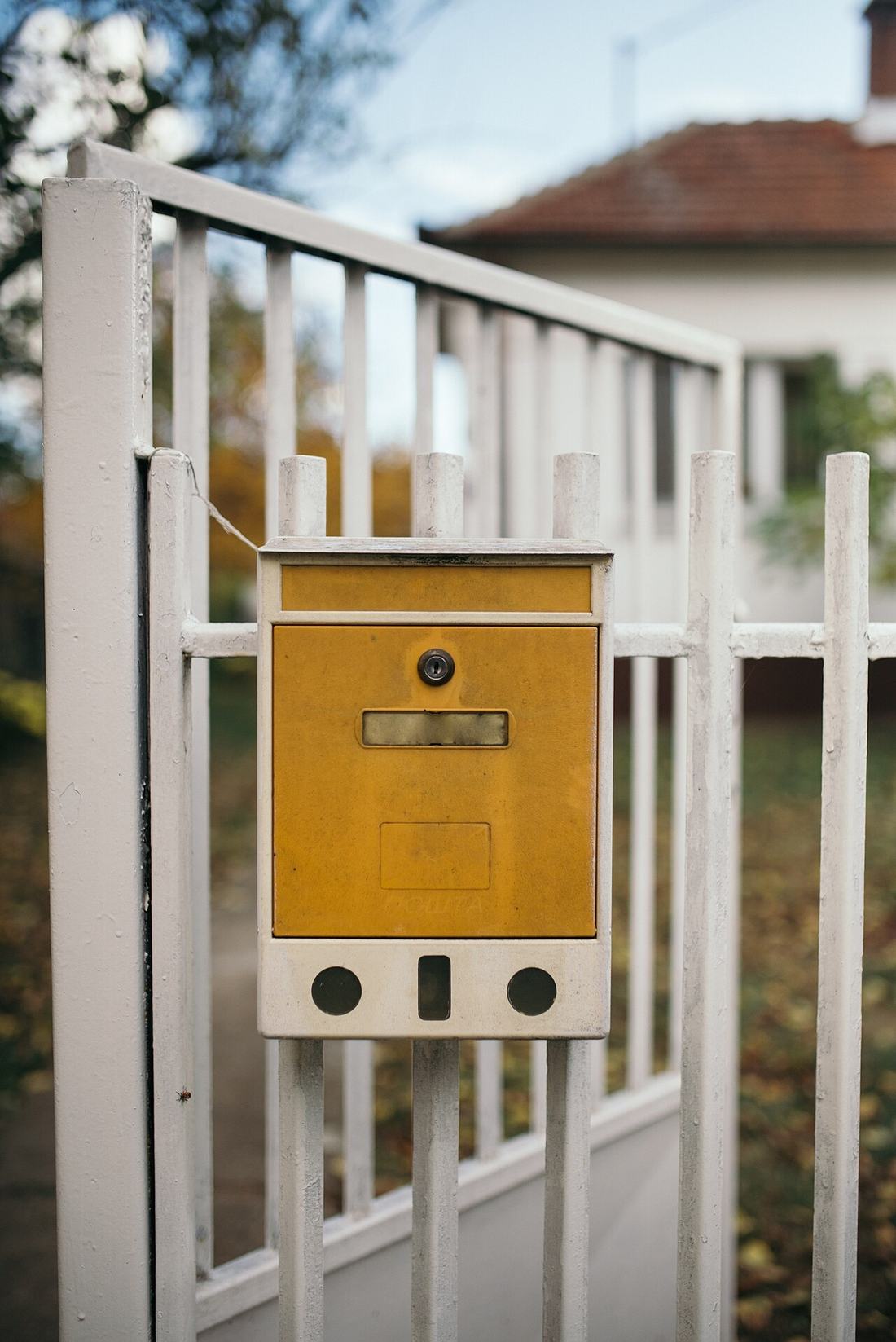 Gelber Briefkasten an einem Gartentor