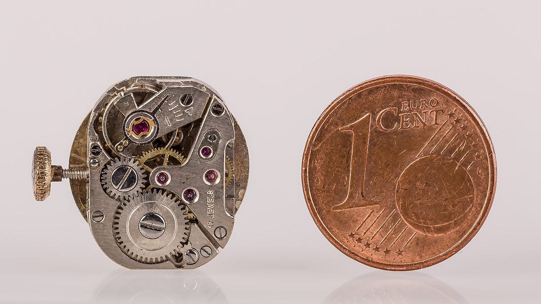 Eine 1-Cent-Münze neben einem Uhrwerk
